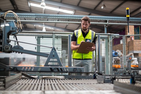 Factory worker maintaining record on clipboard in factory