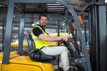 Portrait of smiling factory worker driving forklift