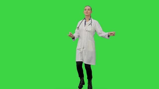 Smiling young woman in lab coat making funny dance on a Green Screen, Chroma Key.