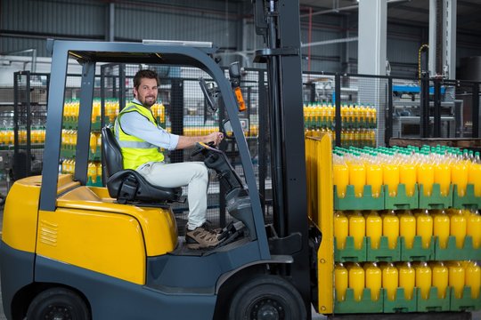 Factory worker loading packed juice bottles 