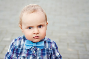 Portrait of little boy in blue checkered shirt and bow tie