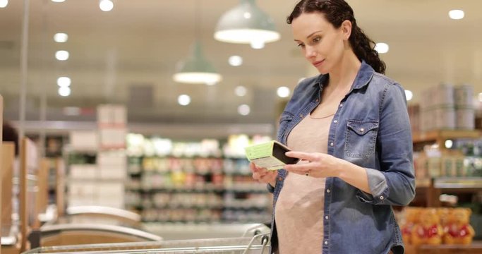 Pregnant woman looking at ready meal in grocery store