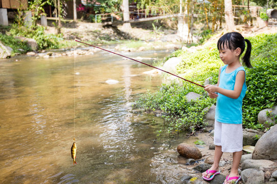 Happy Asian Chinese little girl angling with fishing rod