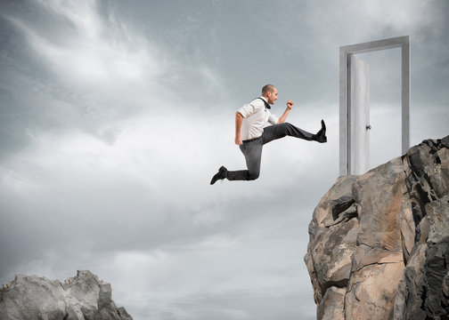 Businessman jumping over the mountains to reach a door