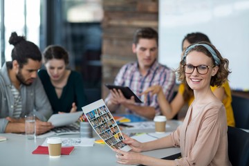 Portrait of smiling graphic designer holding photos in office
