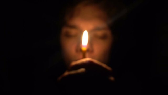 man in dark room hold a candle in front his face