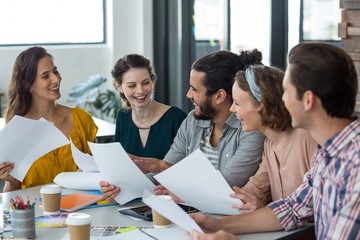 Happy graphic designers laughing while discussing in meeting