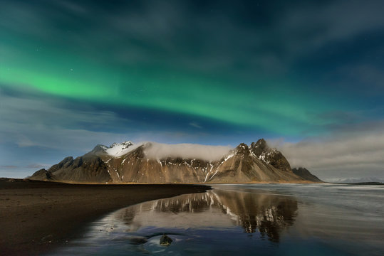 Paisagem nocturna na Islândia. Surpreendente Aurora Boreal na montanha de Vestrahorn com dunas de areia preta, em Stokksnes, Islândia