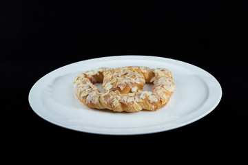 Beautiful traditional european sweet Pretzel (German Bretzel, Brezl, Breze) on a white dish with black background