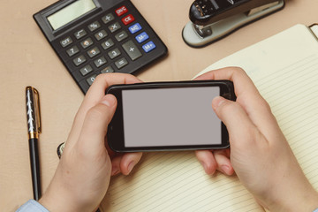 Closeup of a man pointing finger to smartphone with a blank screen monitor