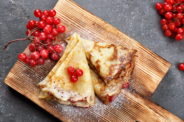 Delicious pancakes with viburnum on wooden board