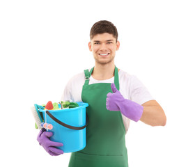 Young man holding bucket with cleaning supplies on white background