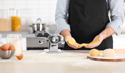 Man with pasta machine on table at kitchen