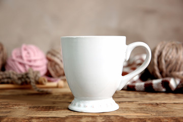 White cup and yarn balls on wooden table