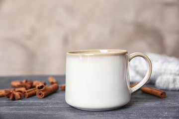 White cup and cinnamon sticks on grey table
