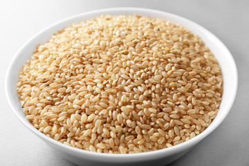 Bowl with raw brown rice on table