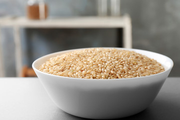 Bowl with raw brown rice on table