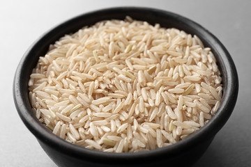 Bowl with raw brown rice on table
