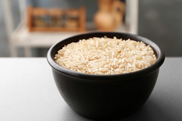 Bowl with raw brown rice on table