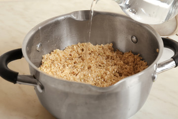 Pouring water into pan with brown rice, closeup