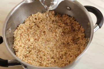 Pouring water into pan with brown rice, closeup