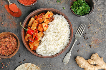Chicken tikka masala with rice in wooden bowl and ingredients on table