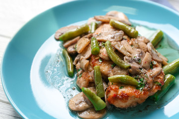 Chicken marsala with mushrooms and French beans on plate, closeup