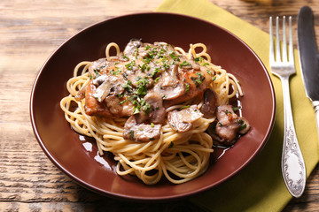 Plate with delicious chicken marsala and spaghetti on table