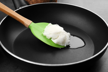 Spoon with coconut oil on frying pan