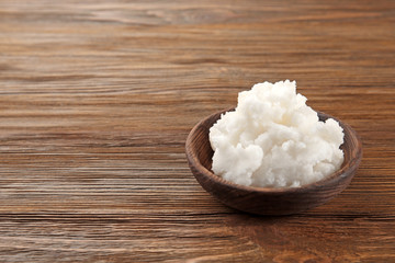 Bowl with coconut oil on wooden background