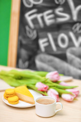 Cup of coffee, tasty cake and beautiful bouquet of flowers on table in cafe