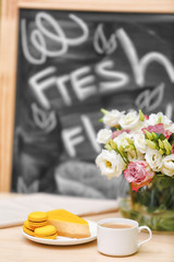 Cup of coffee, tasty cake and beautiful bouquet of flowers on table in cafe