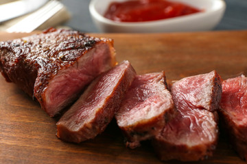 Sliced pieces of delicious medium rare steak on wooden board