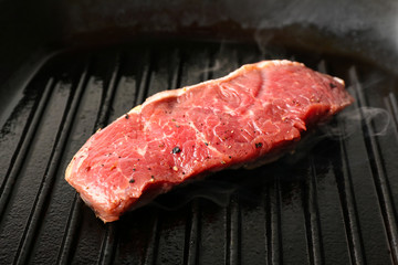Preparing of steak on grill pan, closeup