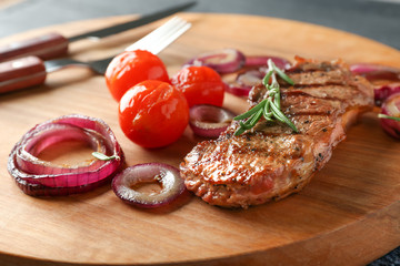 Delicious grilled steak with aromatic rosemary, tomatoes and onion rings on wooden board