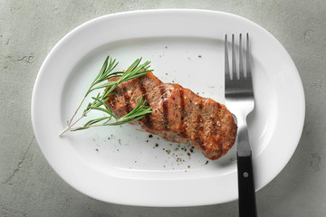 Delicious grilled steak with aromatic rosemary on white plate