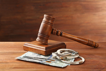 Judge's gavel, handcuffs and money on wooden background