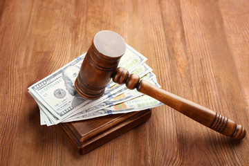 Judge's gavel and dollar banknotes on wooden background