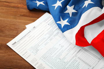 Individual tax return form and American flag on wooden table