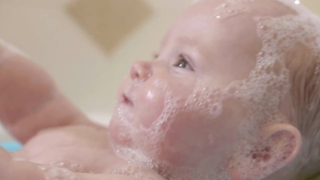 Newborn Baby Covered in Bubbles Close Up Playing and Smiling in Bath