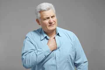 Man with chest pain suffering from heart attack on grey background