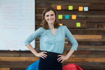 Business executive standing with hands on hip in office