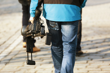 Walking man holding professional camcorder outdoors