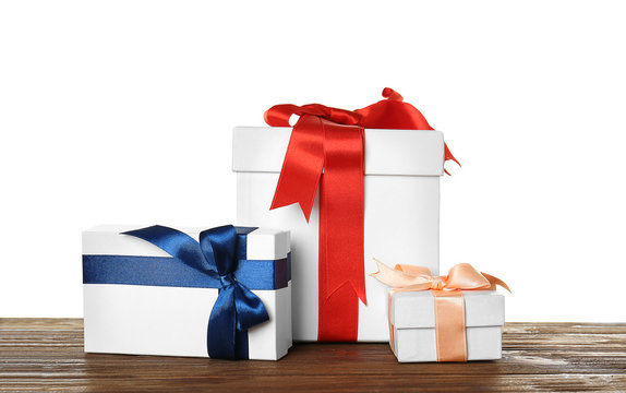 Beautiful white gift boxes with satin ribbons on wooden table