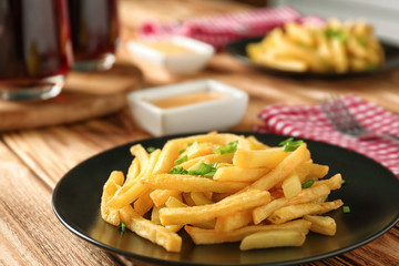 Portion of delicious french fries with onion on dining table