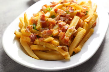 Portion of delicious french fries with bacon and onion, closeup
