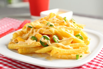 Portion of delicious french fries and cheese sauce, closeup