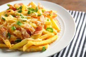 Portion of delicious french fries with bacon and onion, closeup