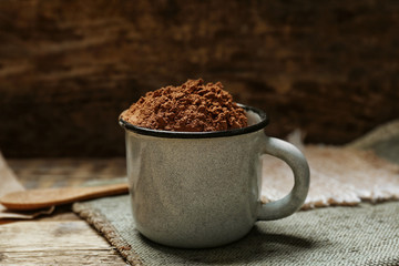Metal mug with cocoa powder on kitchen table