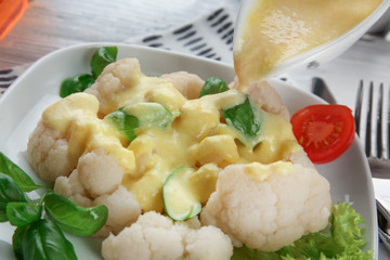 Pouring cauliflower with cheese sauce, closeup